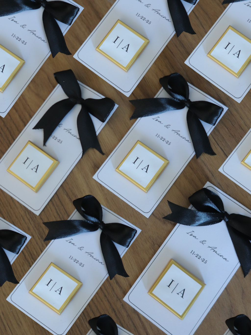 Cards with black ribbons arranged on a wooden surface, 3 wedding chocolate favours gold foil