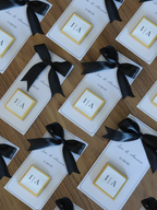 Cards with black ribbons arranged on a wooden surface, 3 wedding chocolate favours gold foil