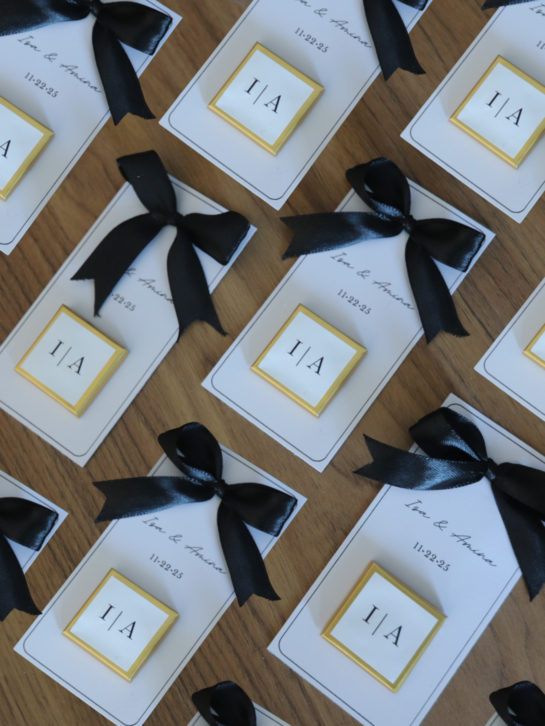 Cards with black ribbons arranged on a wooden surface, 3 wedding chocolate favours gold foil