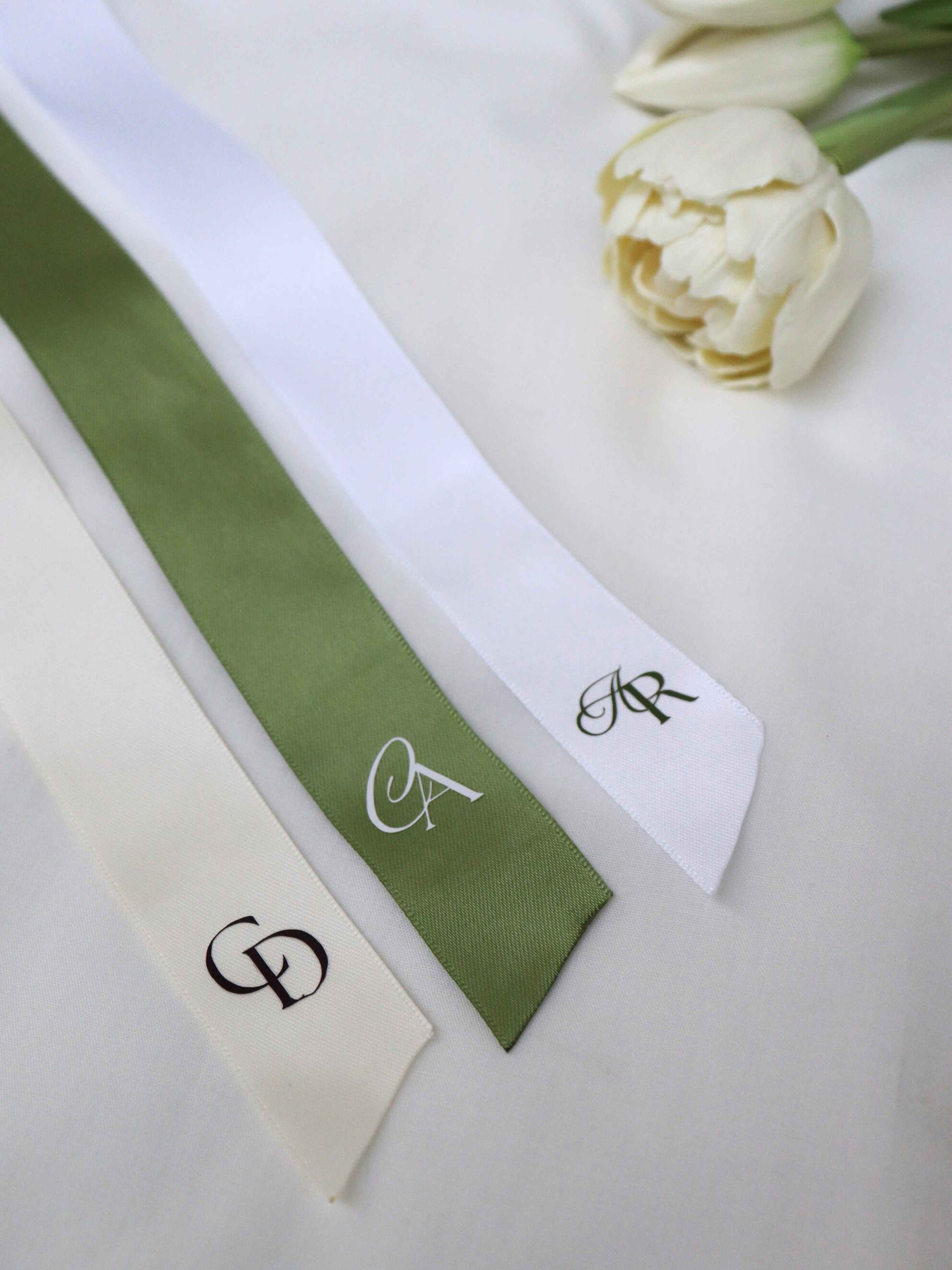 three ribbons with monograms on a white surface with white flowers, Initials Symbol Personalized Ribbon green white ivory monogram