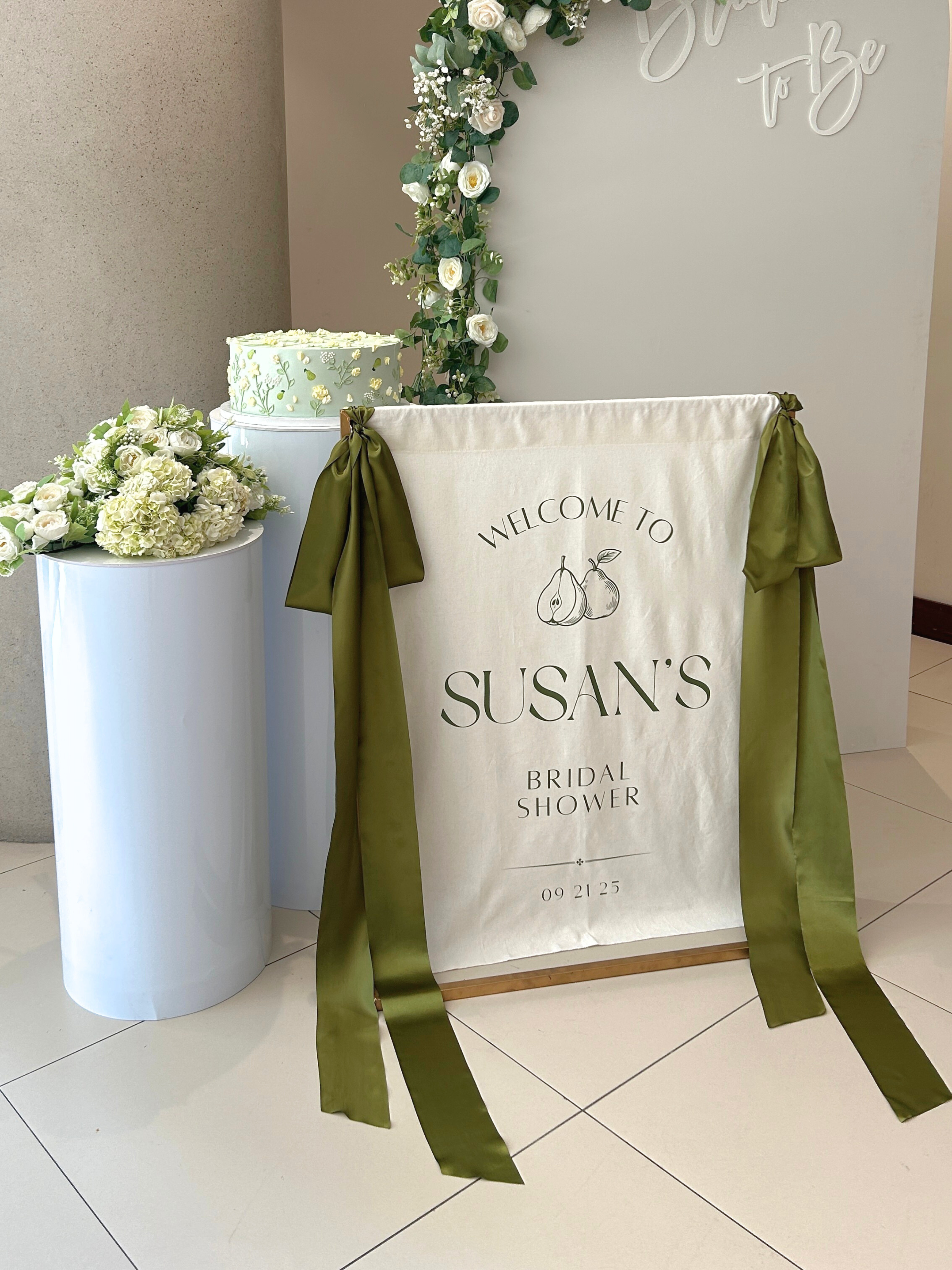 Bridal shower welcome sign with green ribbons and floral decorations.