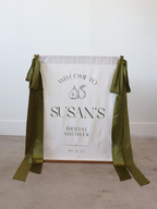 Bridal shower welcome sign with green ribbons on a plain background