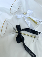Two gold-rimmed glass flutes with black and white ribbons on a white background. bride and groom personalized custom wedding ribbons black and white