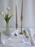 Decorative setup with candles, flowers, and a marble tray on a white surface. bridesmaid proposal ribbon white candle marble tray