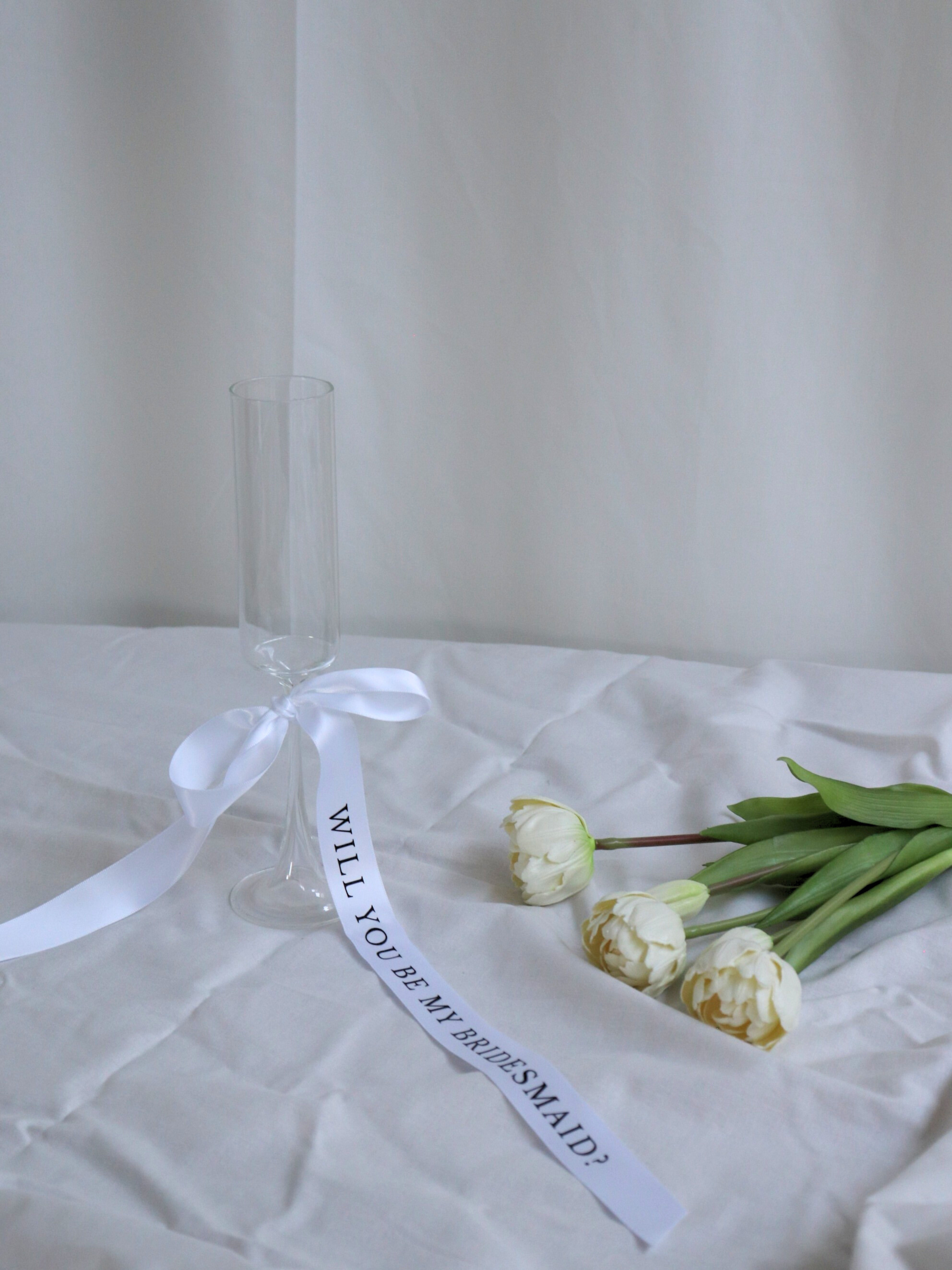 Clear glass with a white ribbon and tulips on a white surface, bridesmaid proposal ribbon white long 