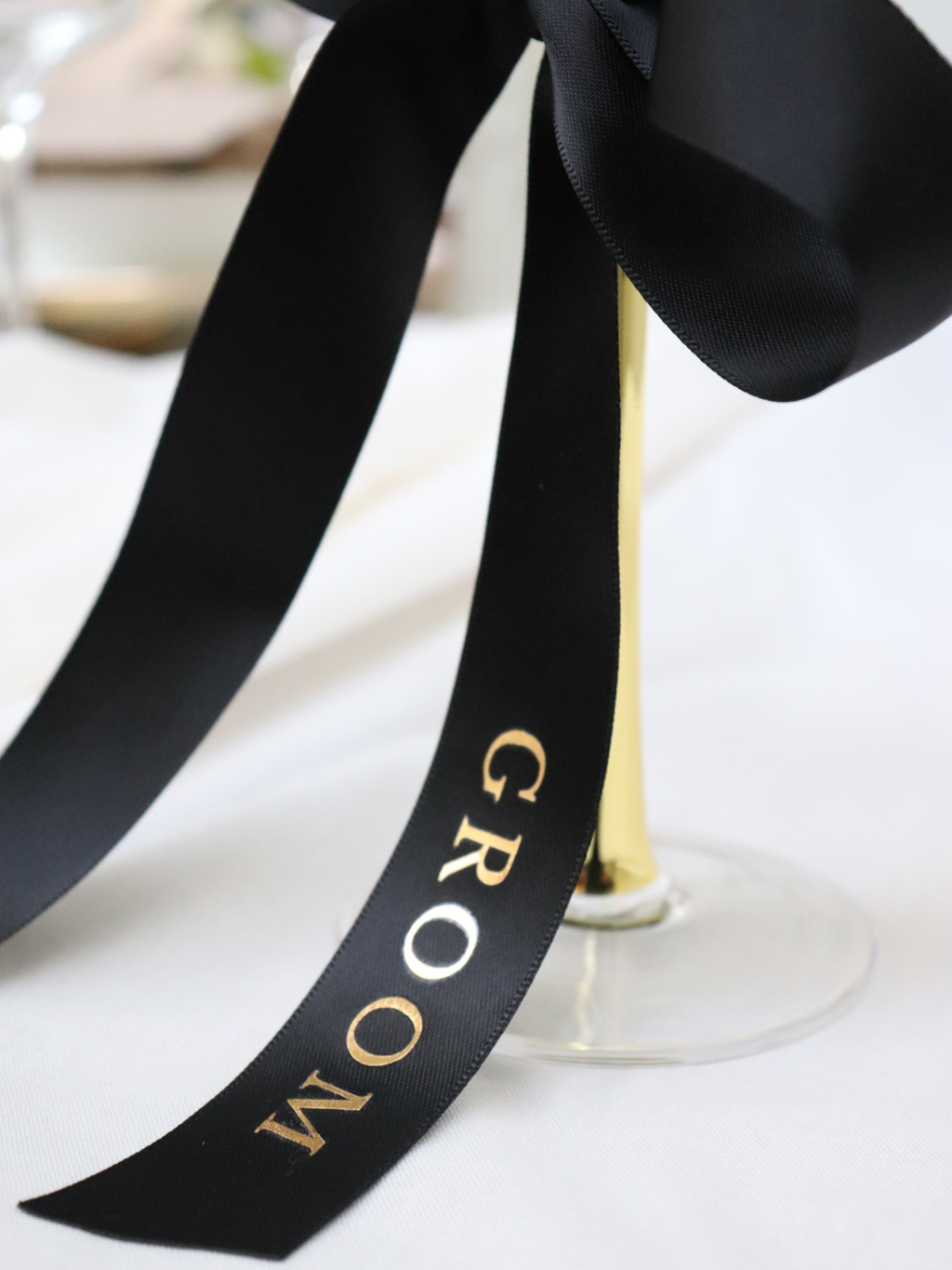 Black ribbon with 'GROOM' text on a white surface. groom gold text white personalized ribbon for wedding